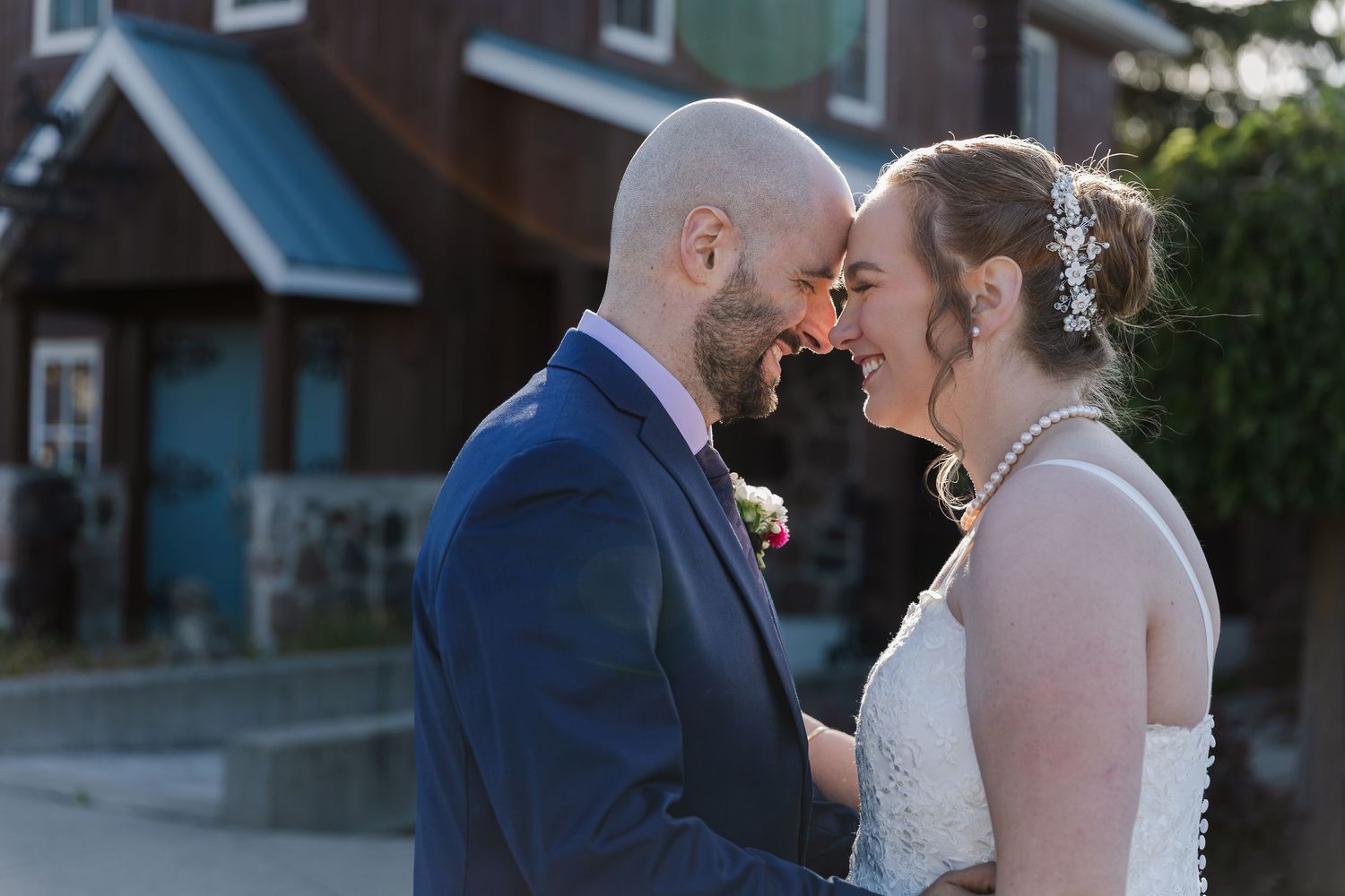 Bride and groom rest foreheads together sharing in each others laughter behind the rustic building at Hauser Hall in Kitchener, Ontario.