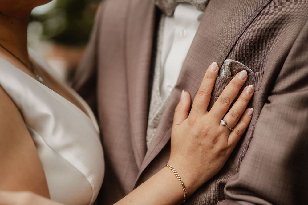 Tender moment between newlyweds in formal attire sharing an intimate embrace outdoors.