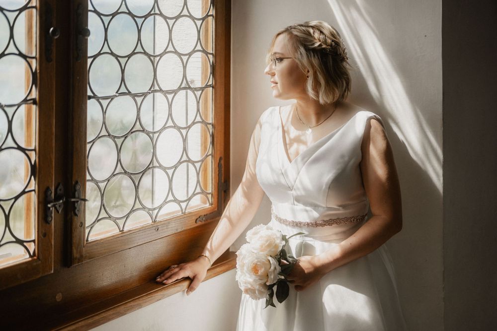 A soft, romantic bridal portrait by a decorative window with delicate lighting.