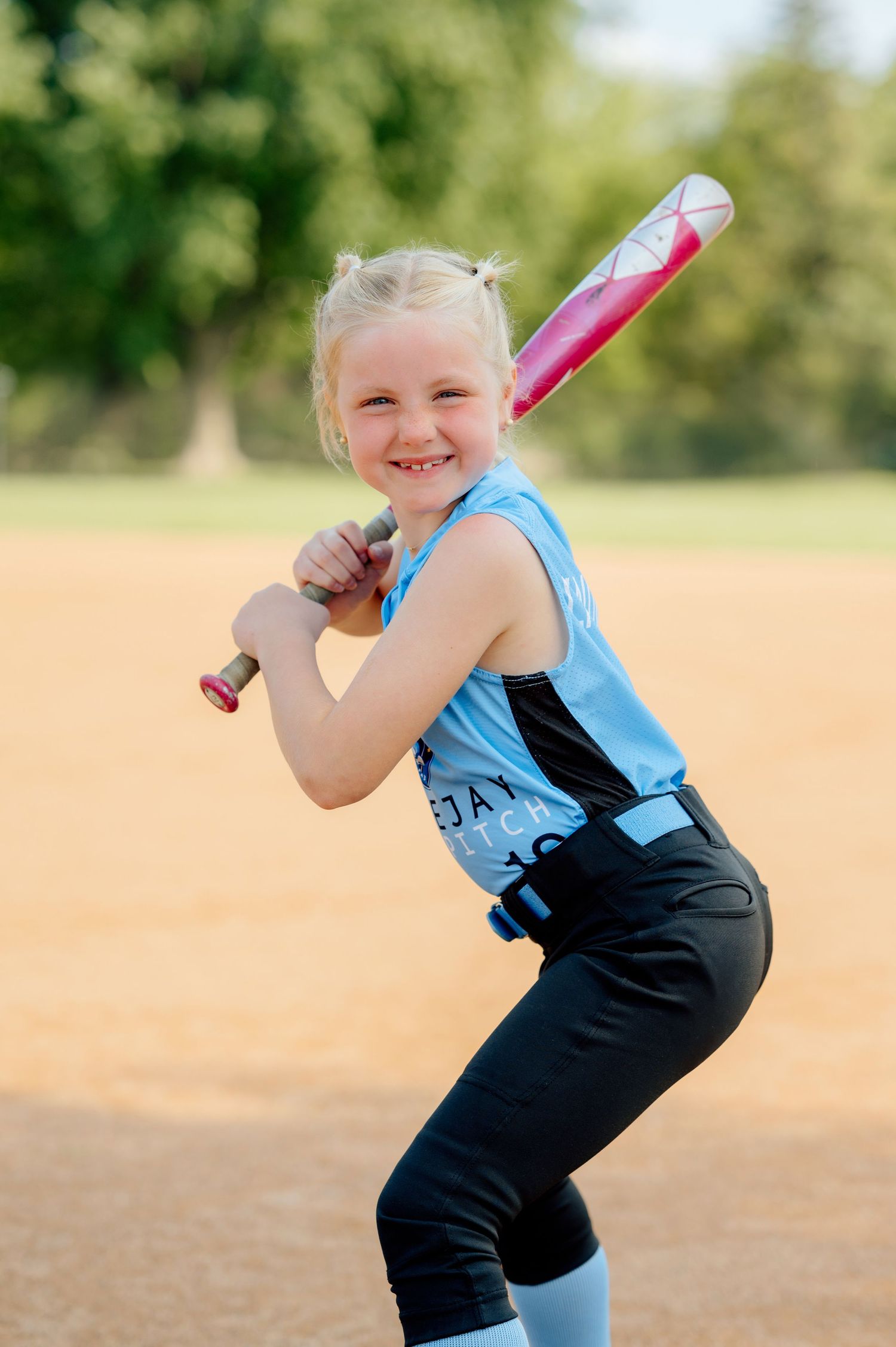 A series of four photos showing a young softball player in a blue and black uniform practicing with a glove on a field.