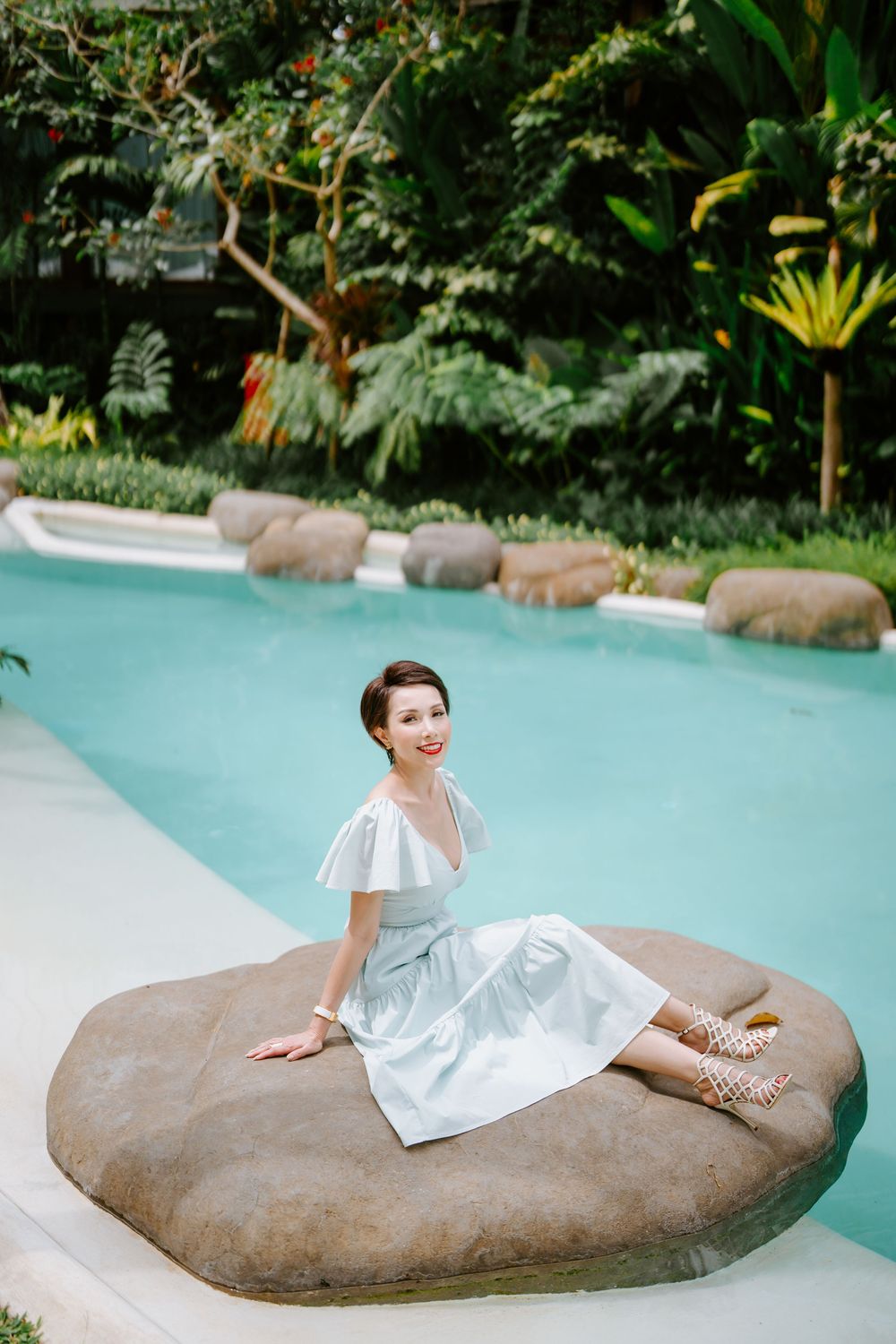 A light summer dress stands out against turquoise pool water and natural rock formations.
