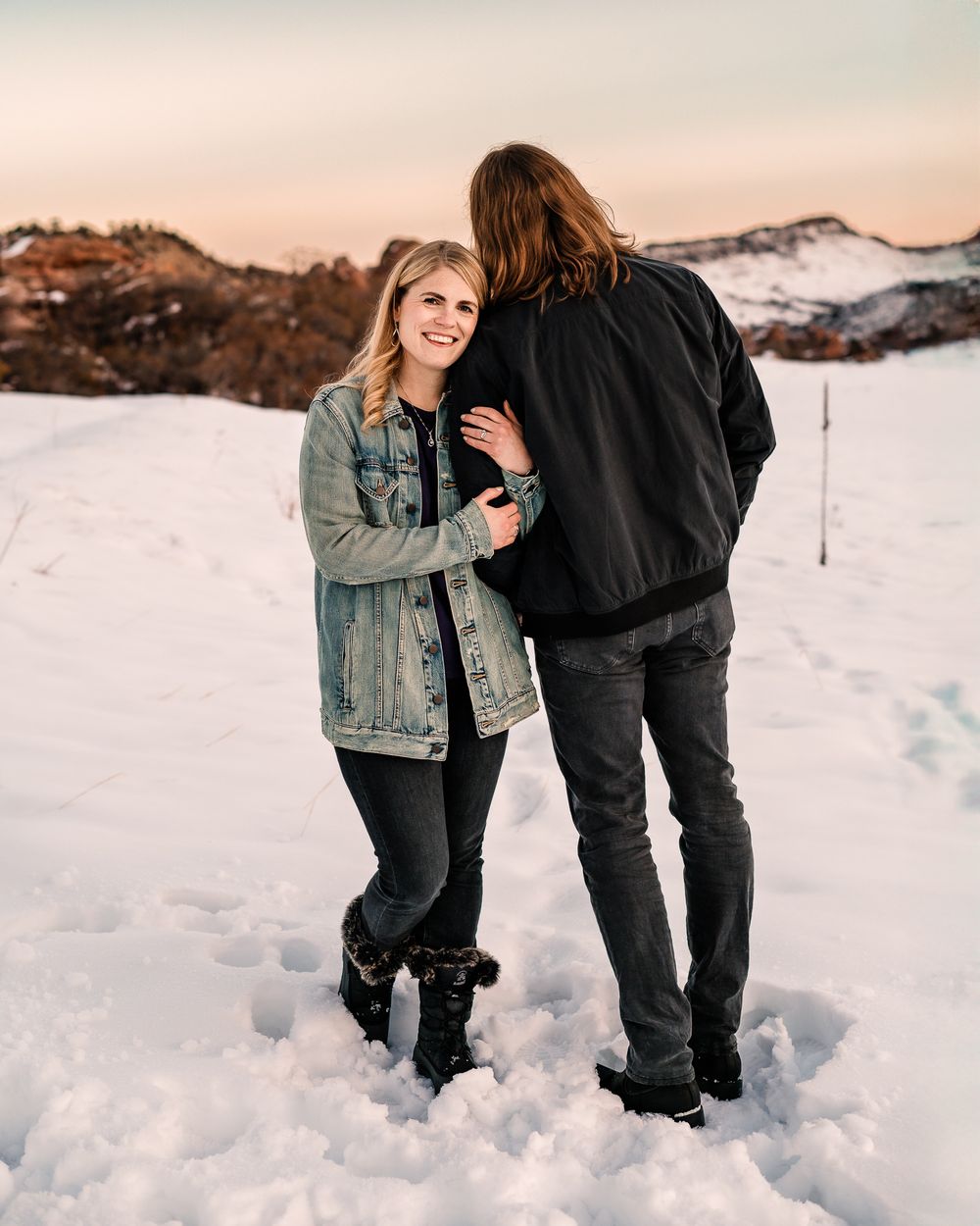 a wife leaning against her husbands shoulder while he gazes into some snowy Littleton, Co mountains