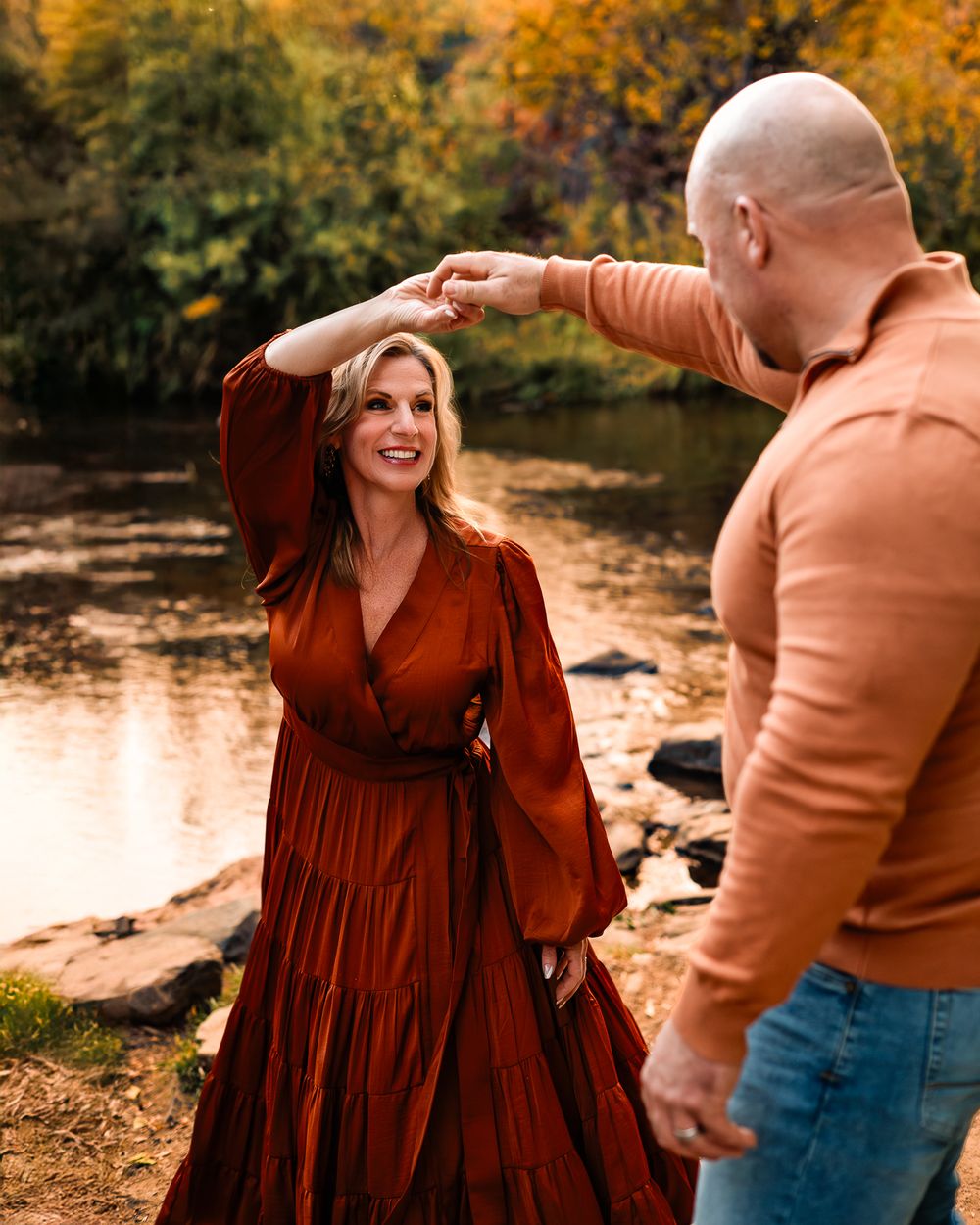 a man twirling his wife around in front of a creek in the Colorado mountains