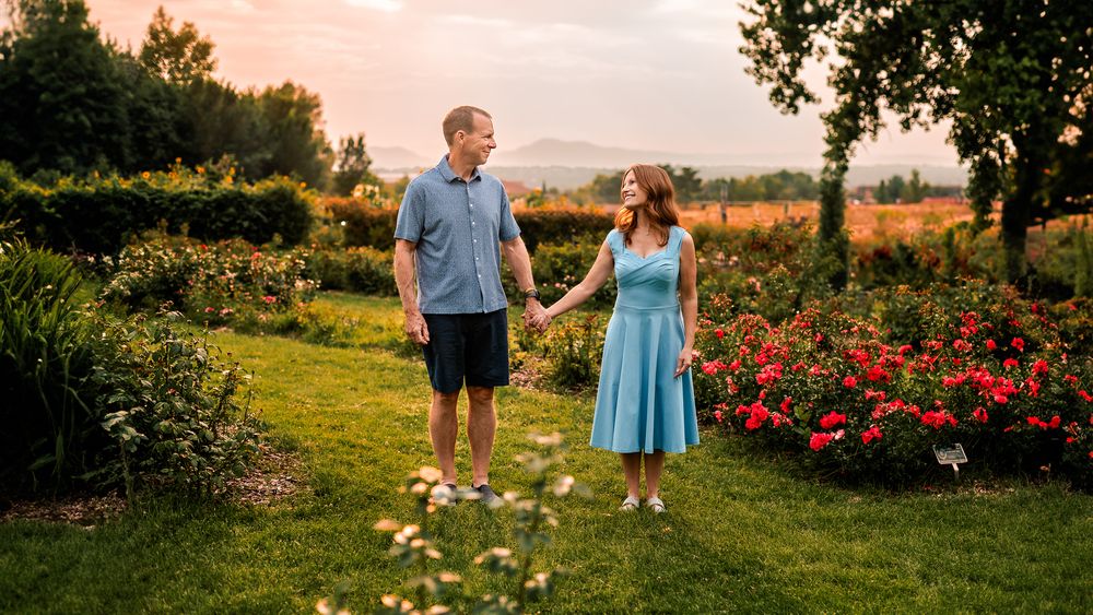 A middle-aged couple looking into one another eyes while surrounded by a flower garden in Littleton, CO