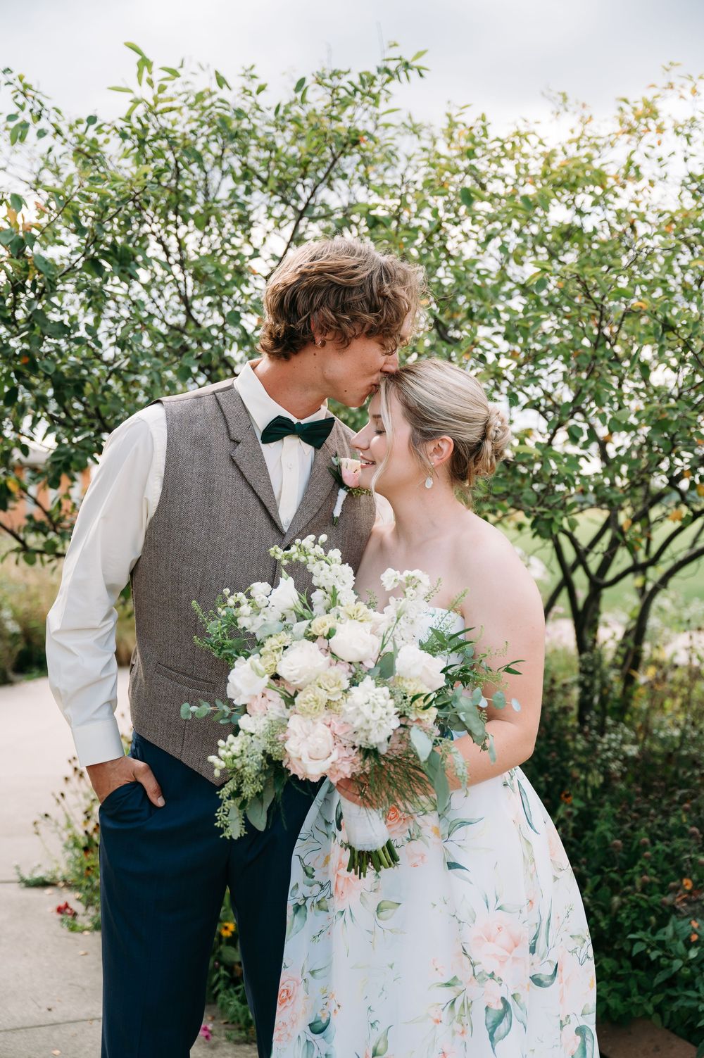 groom kissing brides forehead in front of tree at Lowe Park in Marion Iowa by Midwest wedding photographer Elisa Tonne of Vibe Photo Co