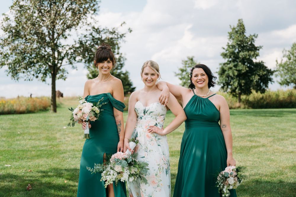 bride in floral print dress with 2 bridesmaids standing beside in Lowe Park Marion Iowa taken by cedar rapids midwest wedding photographer