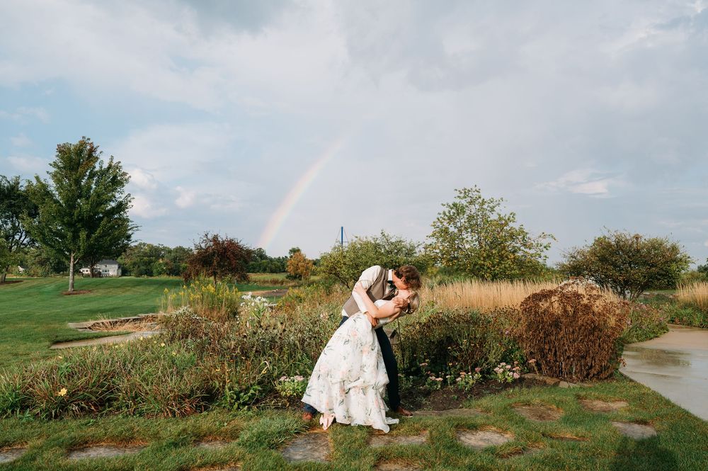 Groom dipping bride for a kiss under rainbow at lowe park marion iowa by midwest cedar rapids wedding photographer
