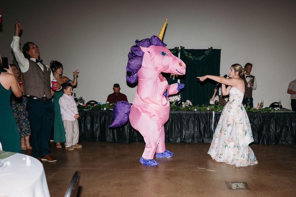 photo of bride during reception with friend dressed in blow up pink pony costume at lowe park in marion iowa by midwest wedding photographer