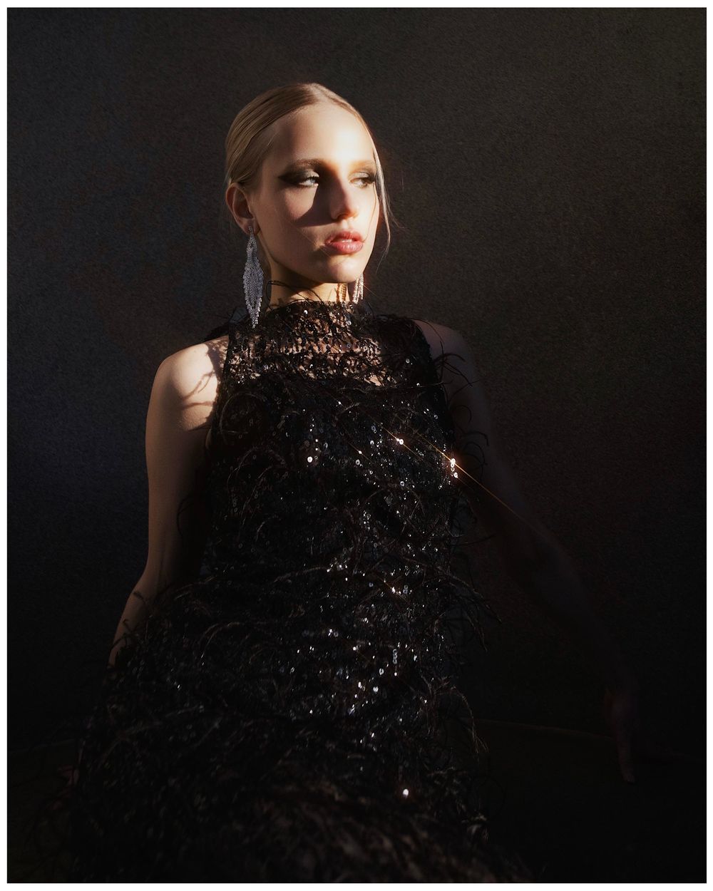 A striking fashion photo series against black background showing dramatic poses with glittering dark fabric.