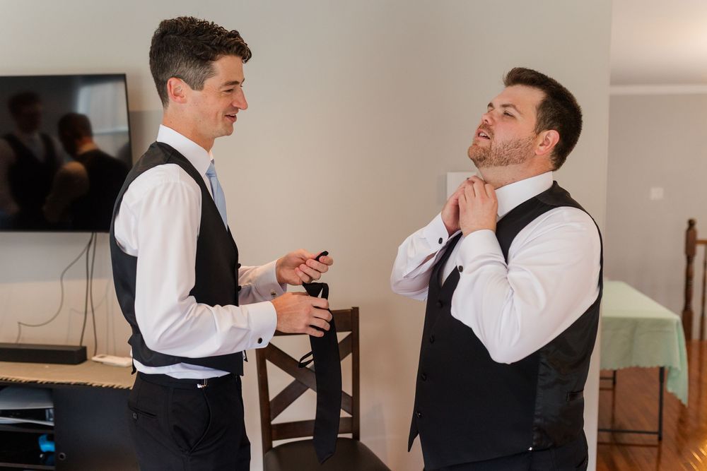 Four sequential shots show someone helping adjust a tie and vest at a formal occasion preparation.