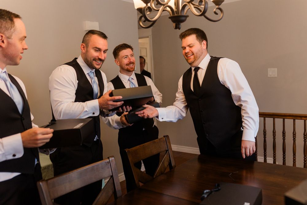 Men in black vests and white shirts gathered around a table reading personal letters and notes.
