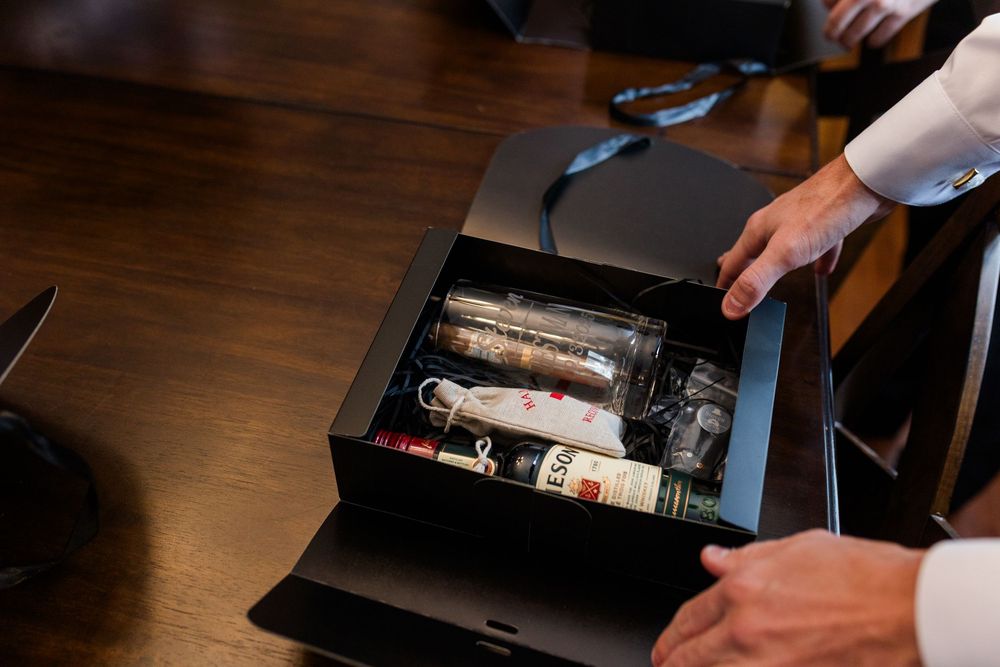 Hands opening a wooden cigar box filled with premium cigars on a dark wooden table.