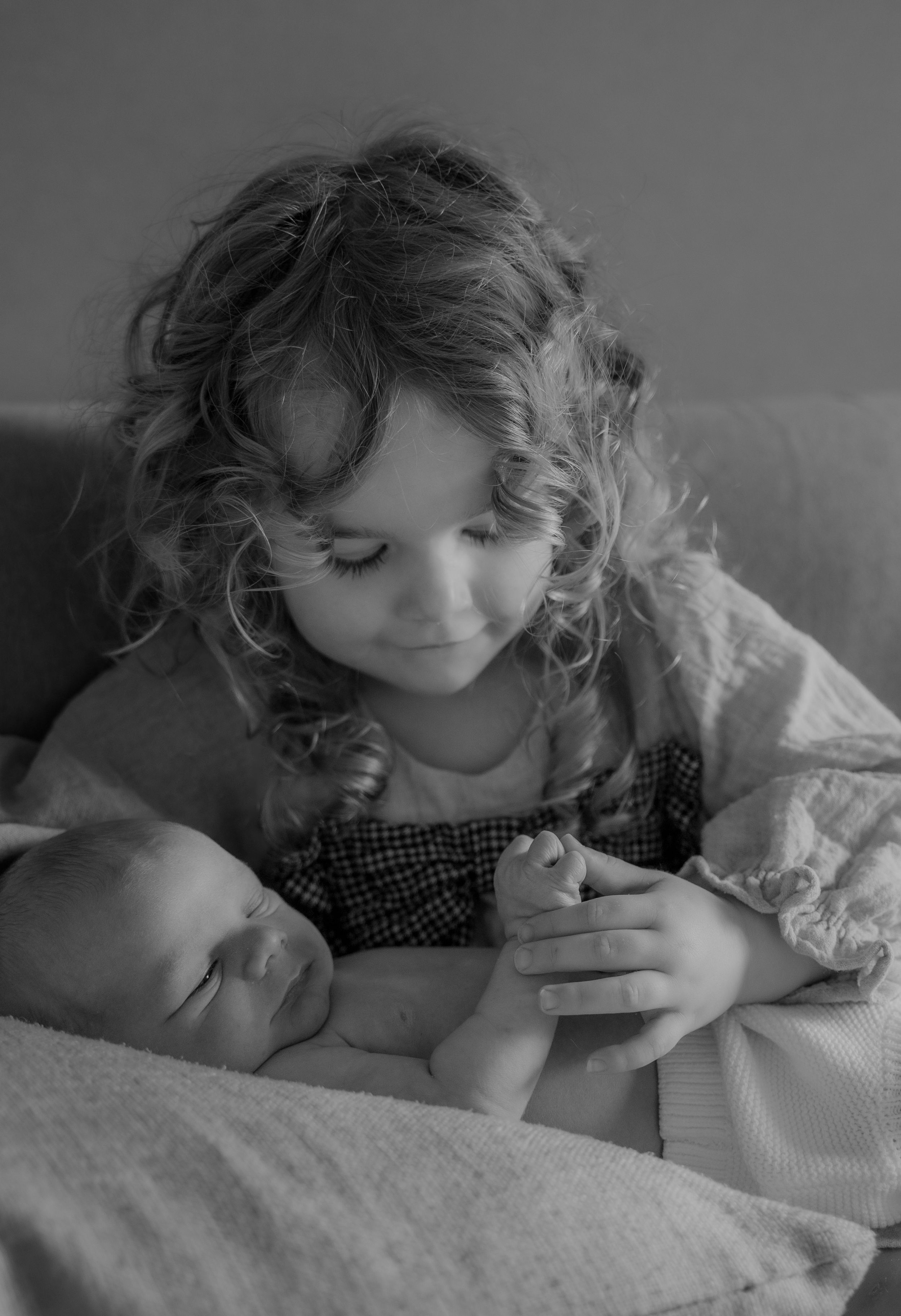 A child lying in bed while looking at a book in black and white.