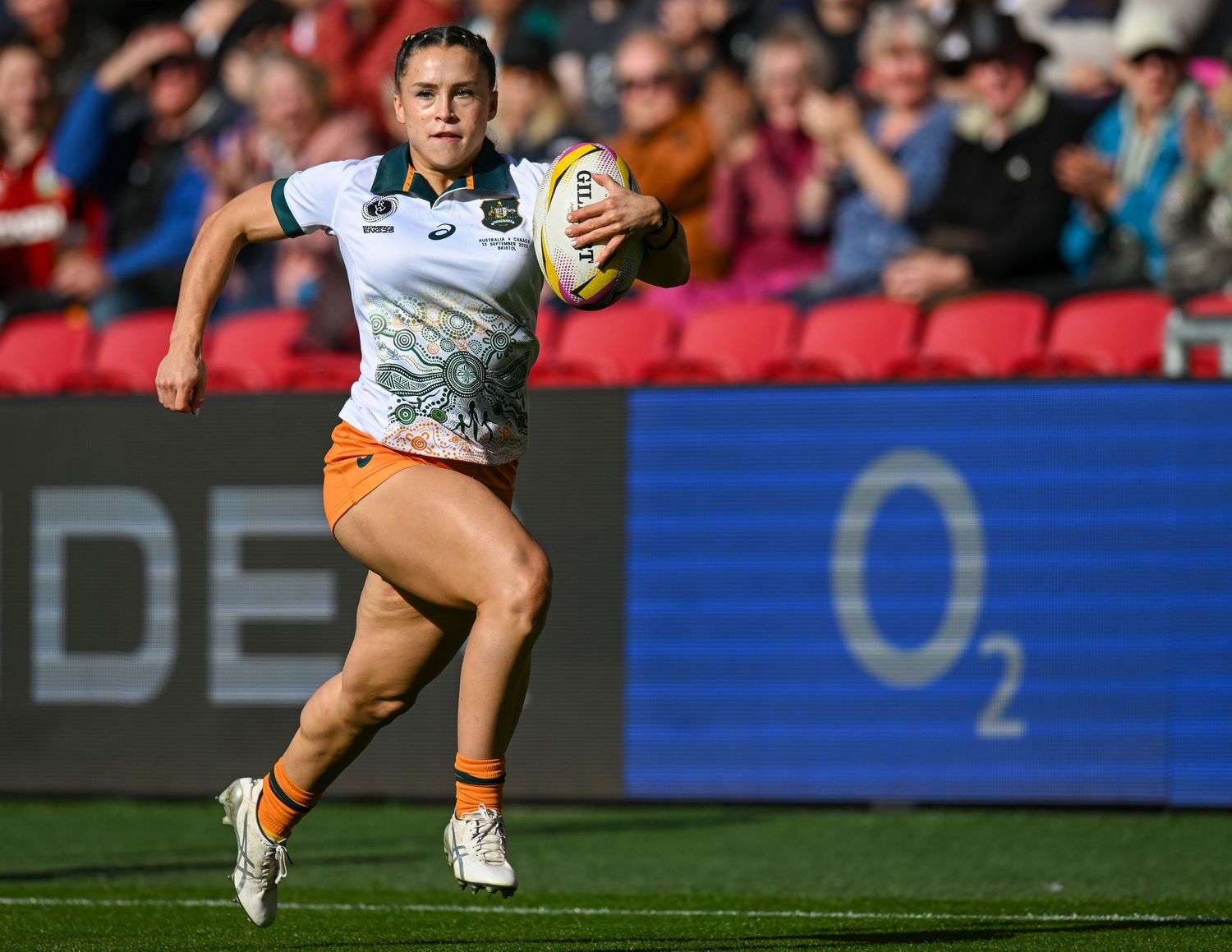 A rugby player in blue and orange uniform runs with the ball during a competitive match.
