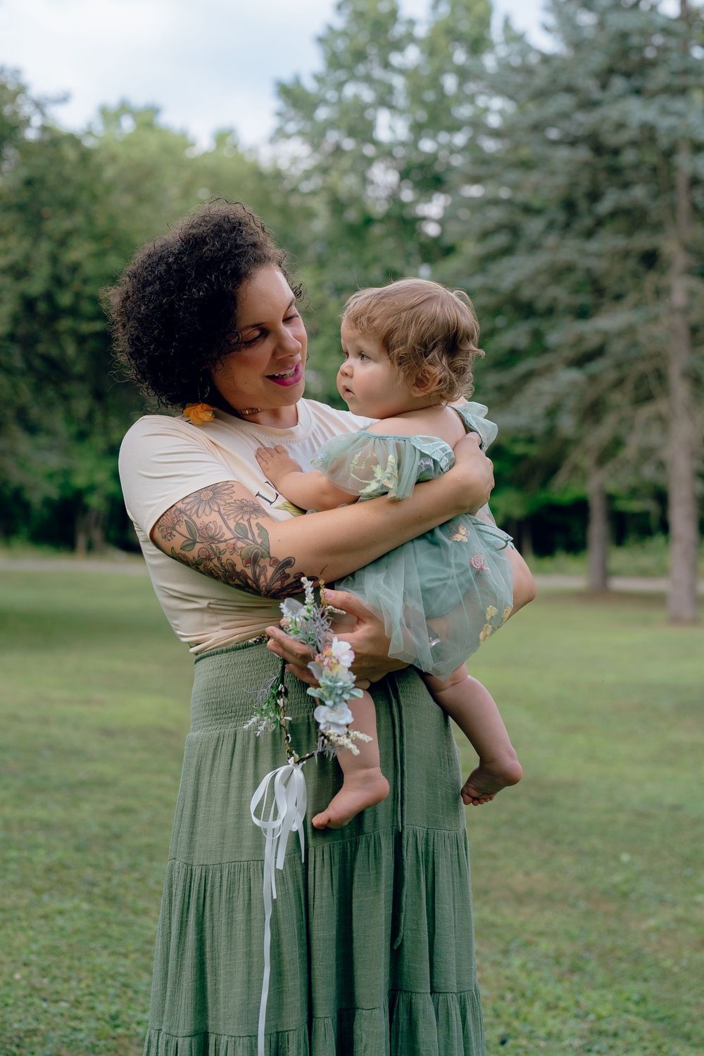 A joyful embrace in a lush garden setting with evergreen trees in the background in Akron, Ohio One Year Milestone Photo Session