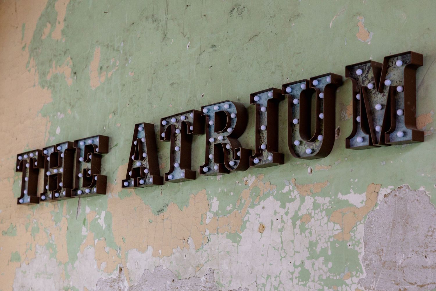 A weathered green wall with vintage distressed text lettering in dark color creates an antique aesthetic effect.