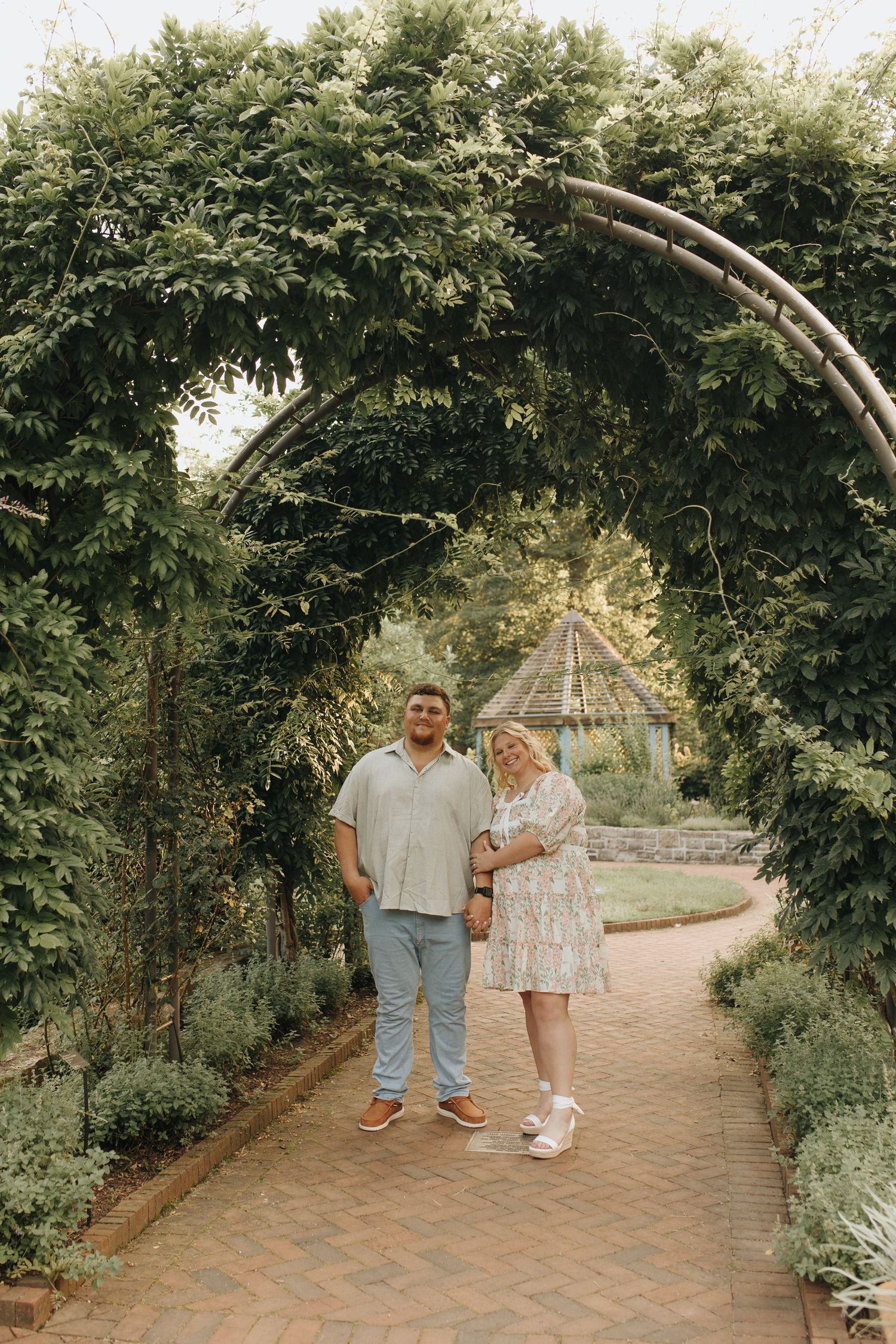 Couple standing side-by-side under beautiful green archway at local metro park in Columbus, Ohio.