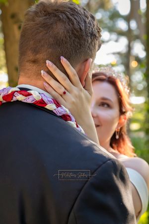 back of groom's head brides hand on his neck with ring in focus