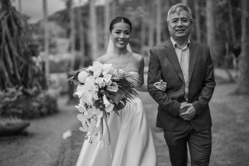 Black and white portrait of wedding party walking through garden setting.
