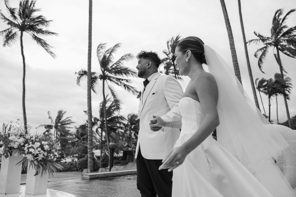 Black and white photo of beachside wedding reception under swaying palm trees.