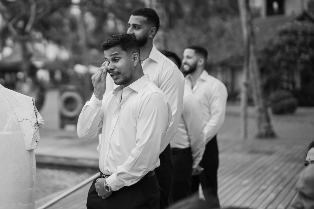 Wedding guests mingle during outdoor cocktail hour in tropical setting.