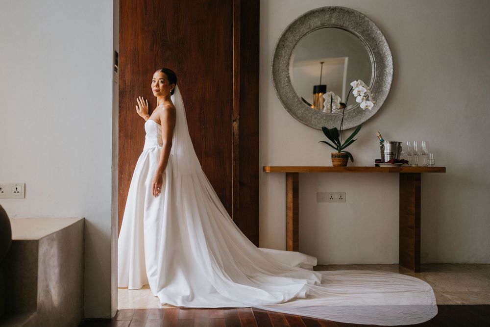 Wedding preparation scene in an elegant bedroom with a flowing white gown.