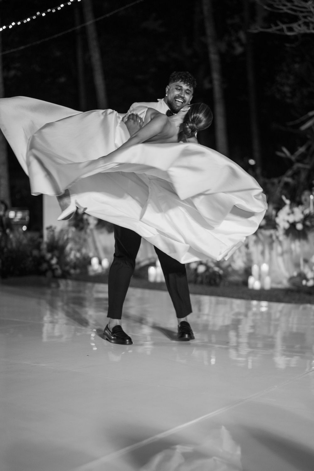 Black and white photo of dancing on reflective floor at wedding reception.