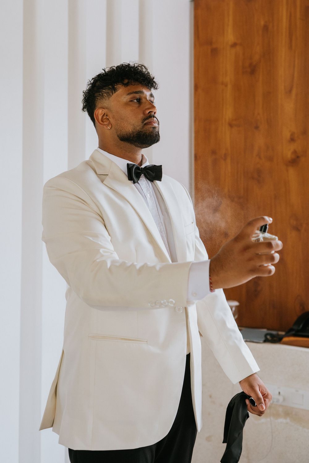 Groomsmen in white tuxedo jackets prepare for wedding celebration in elegant indoor setting.