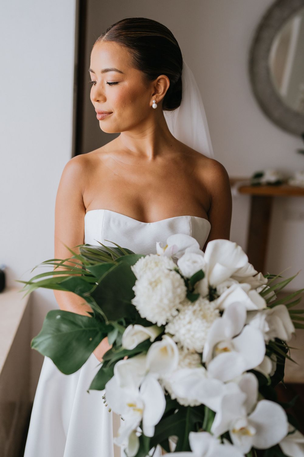 Close-up of elegant white orchid and rose bridal bouquet with tropical greenery.