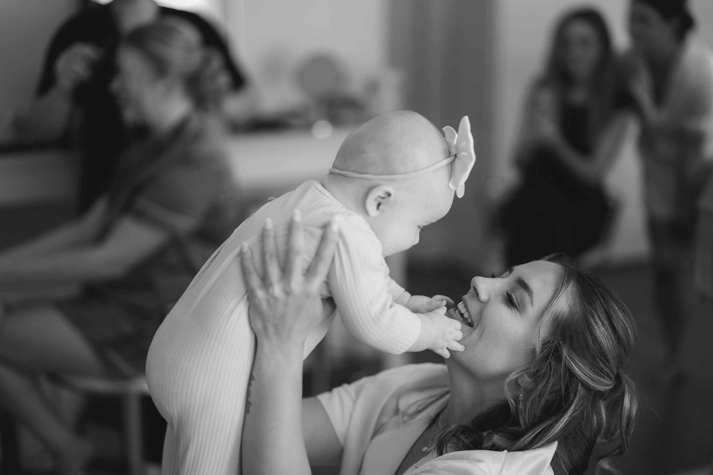 A touching black and white moment between parent and baby as they share a playful embrace while lying down.