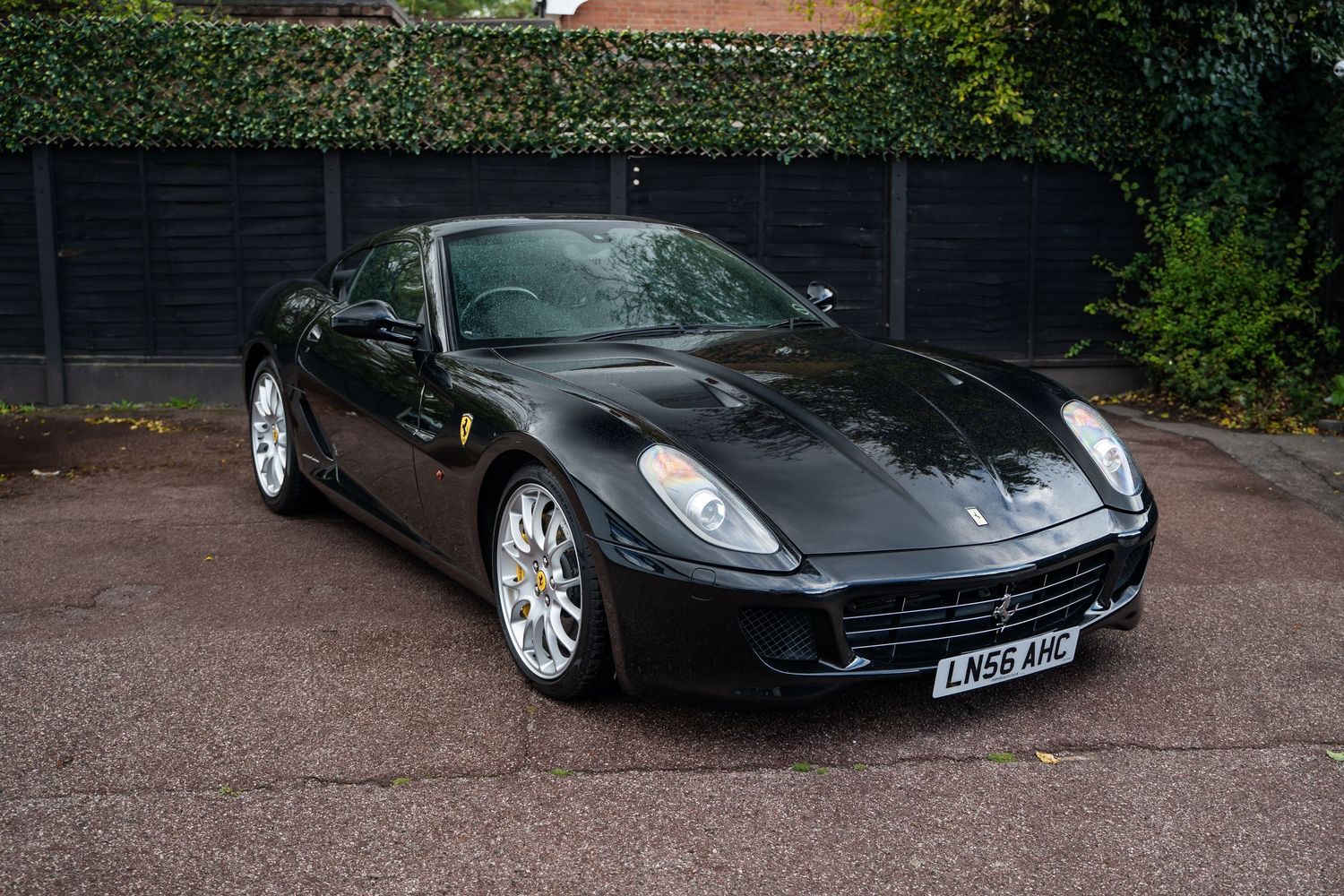 Black Ferrari 599 GTB with silver alloy wheels photographed in residential driveway.