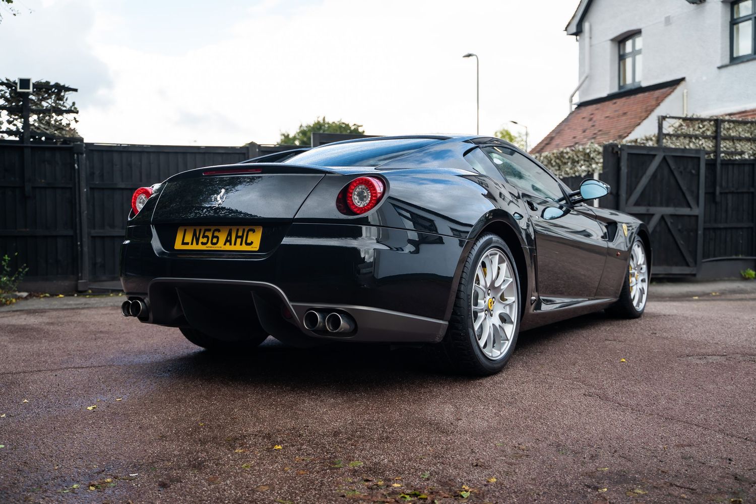 Rear view of black Ferrari 599 GTB showing distinctive taillights and quad exhaust pipes.