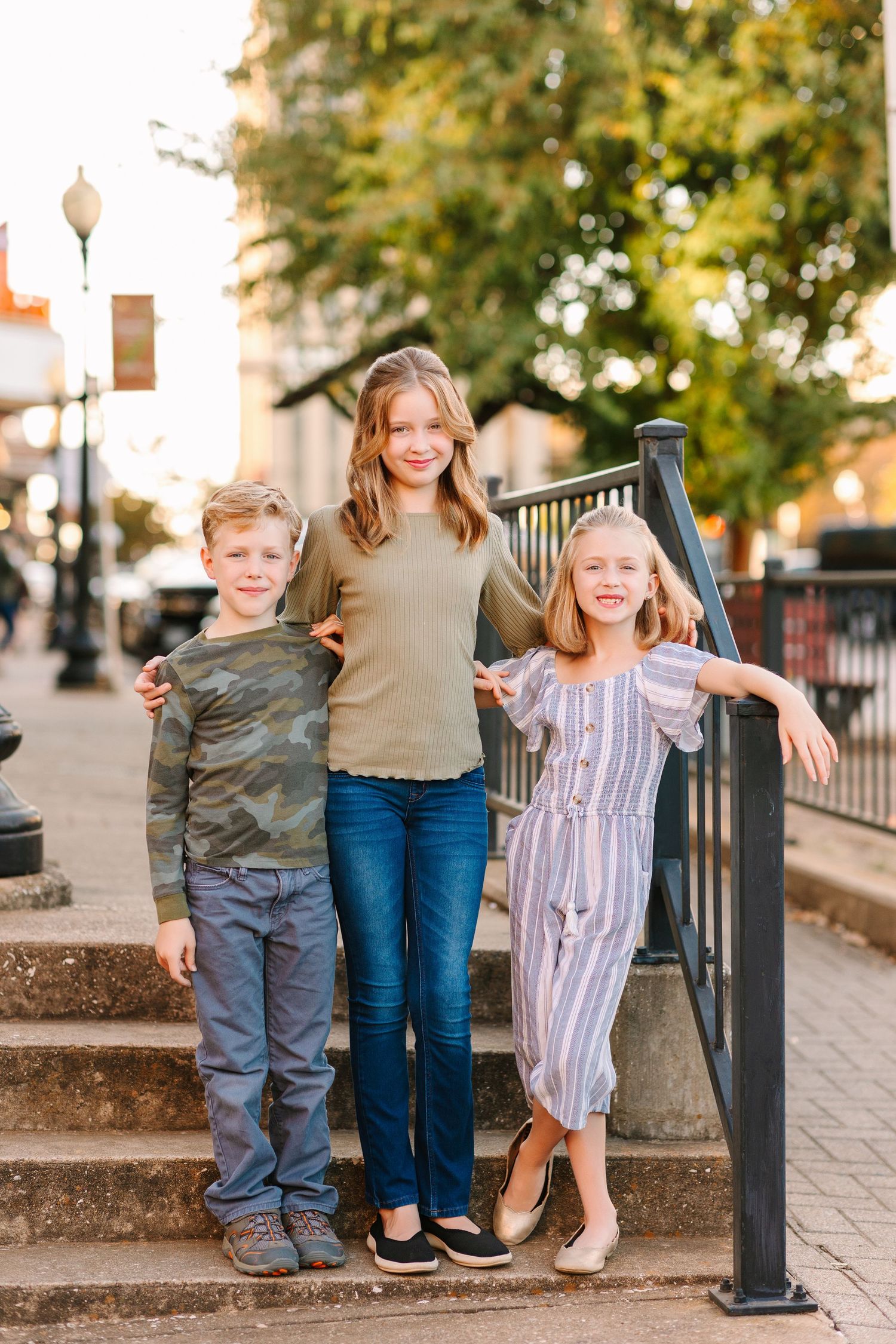 Family members stand together on a brick sidewalk during a warm autumn day with golden trees in background.