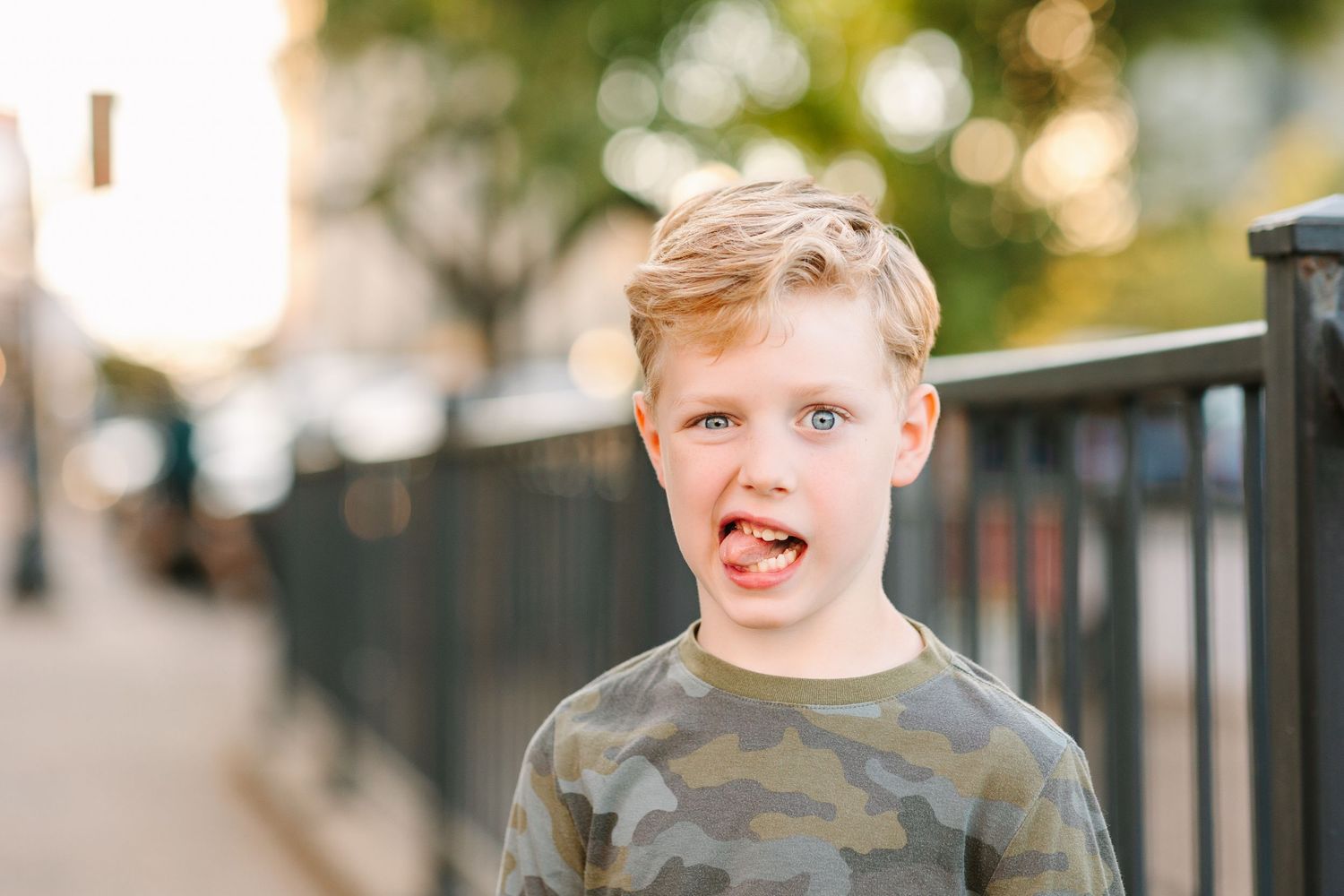 Candid portrait in natural outdoor lighting with iron fence in background showing authentic expression and emotion.