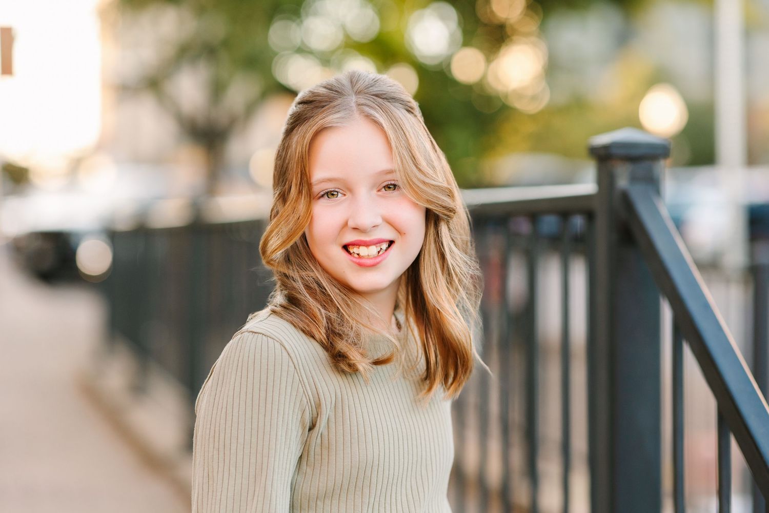A cheerful portrait outside with natural golden sunlight and a ribbed beige sweater.