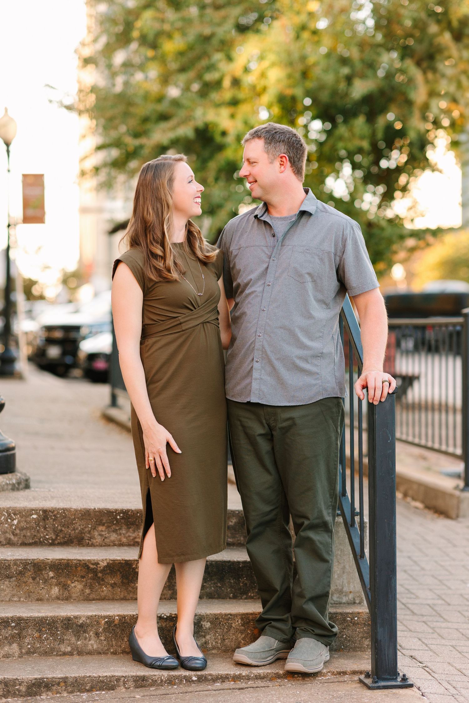 Couple sharing candid moments while sitting on outdoor stone steps with trees in background.