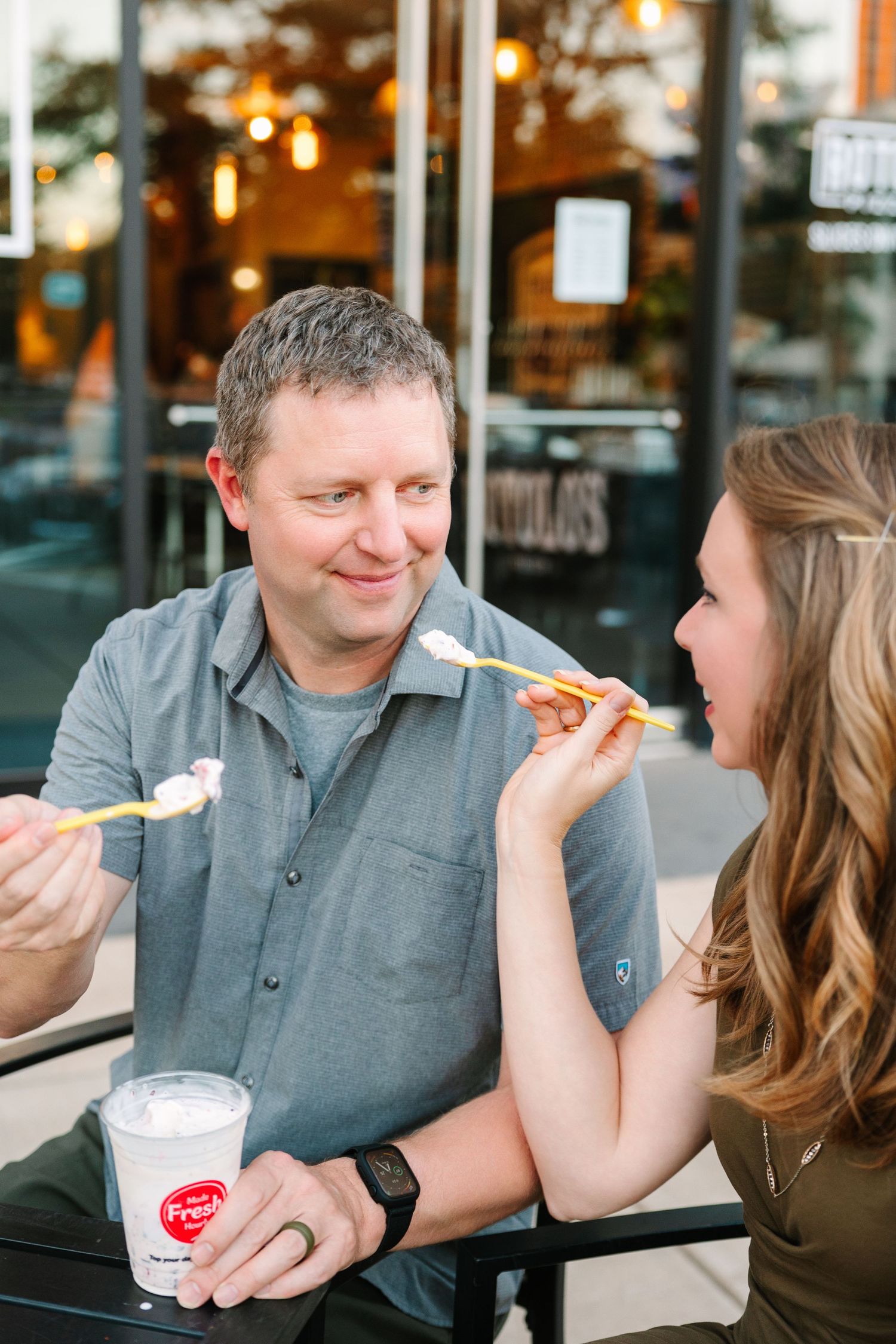 A couple shares pizza and ice cream while dining at an outdoor cafe with evening lighting.