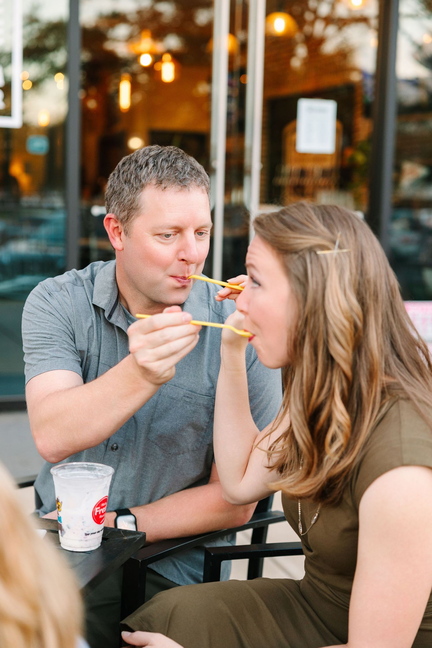 Couple shares fast food while sitting outside at a restaurant patio in the evening.