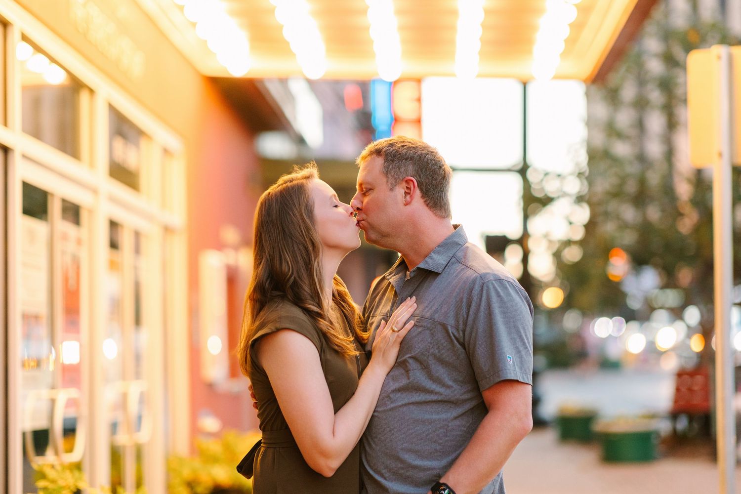 A couple shares an intimate moment together on a city street at dusk.
