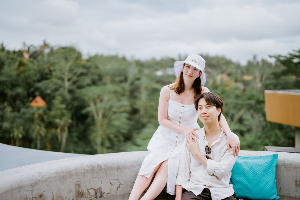 Couple relaxing on outdoor terrace with tropical forest backdrop.