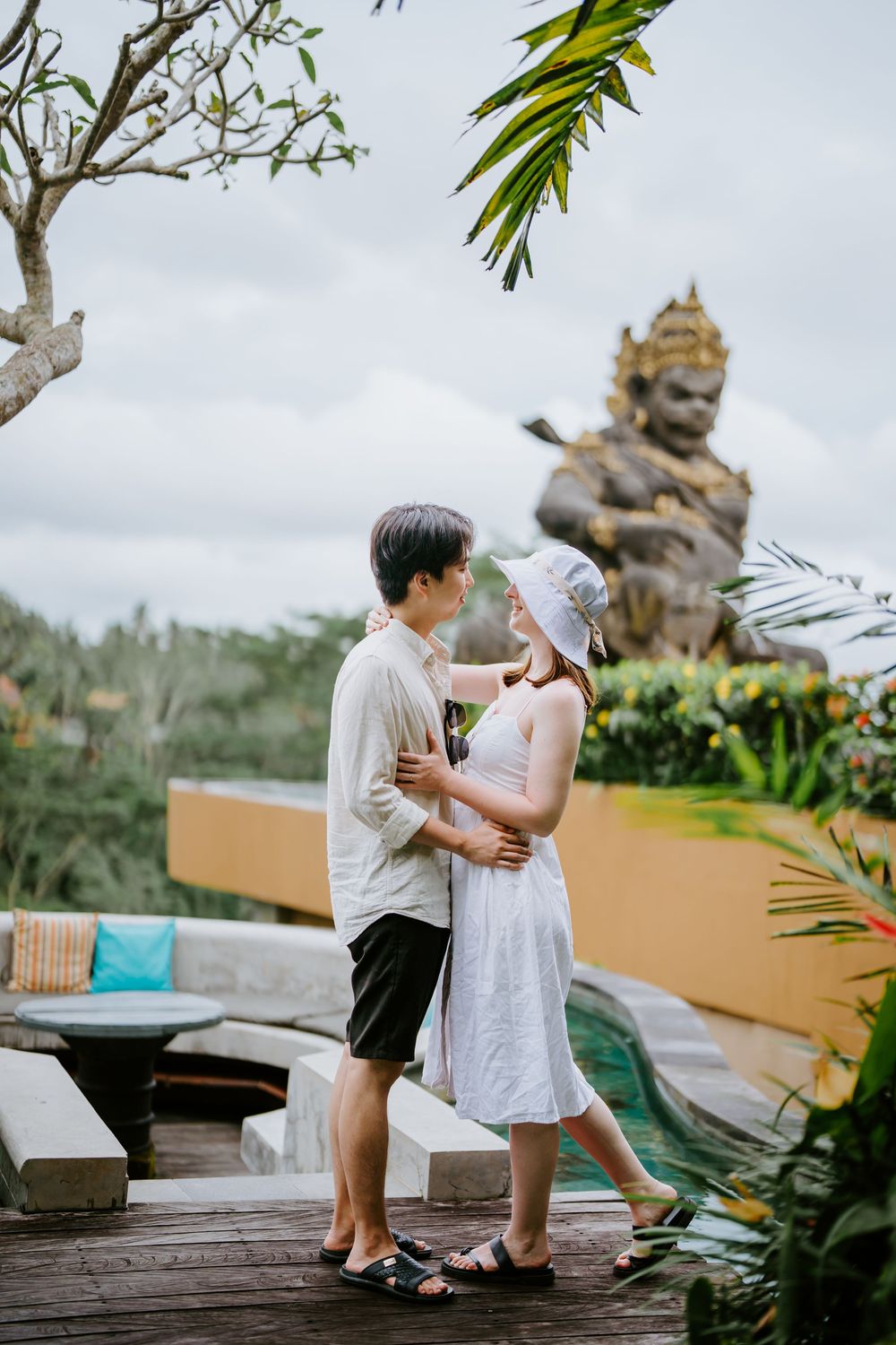 Romantic scene on tropical terrace with traditional Balinese statue in background.