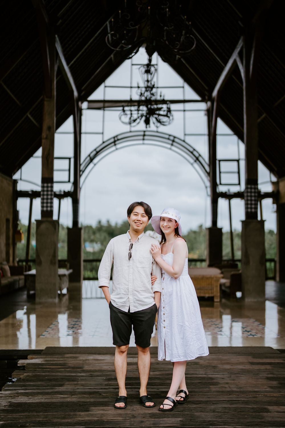 Couple standing under an elegant archway with chandeliers and architectural details.