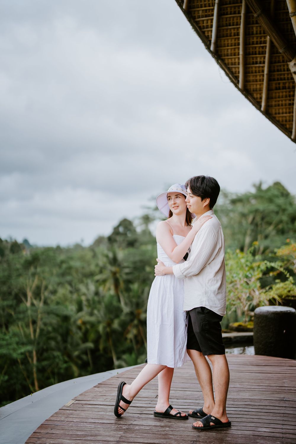 Two people in coordinating white outfits share playful moments on an elevated wooden deck.