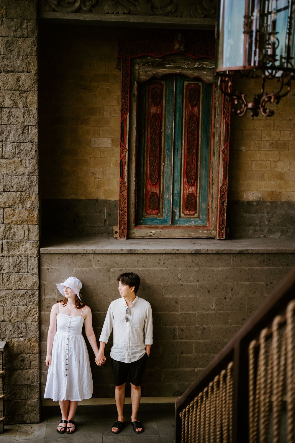 Couple posing against rustic wall with vintage turquoise door in background.