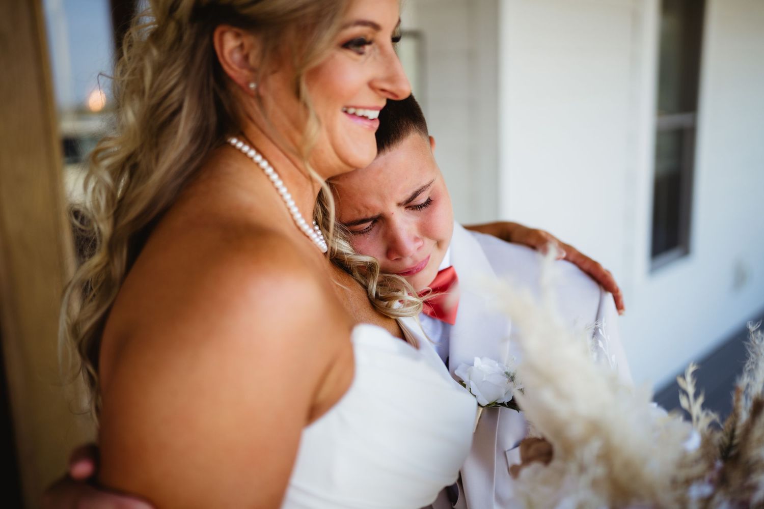 Two people embrace and share a tender moment during a joyful wedding celebration with natural lighting.