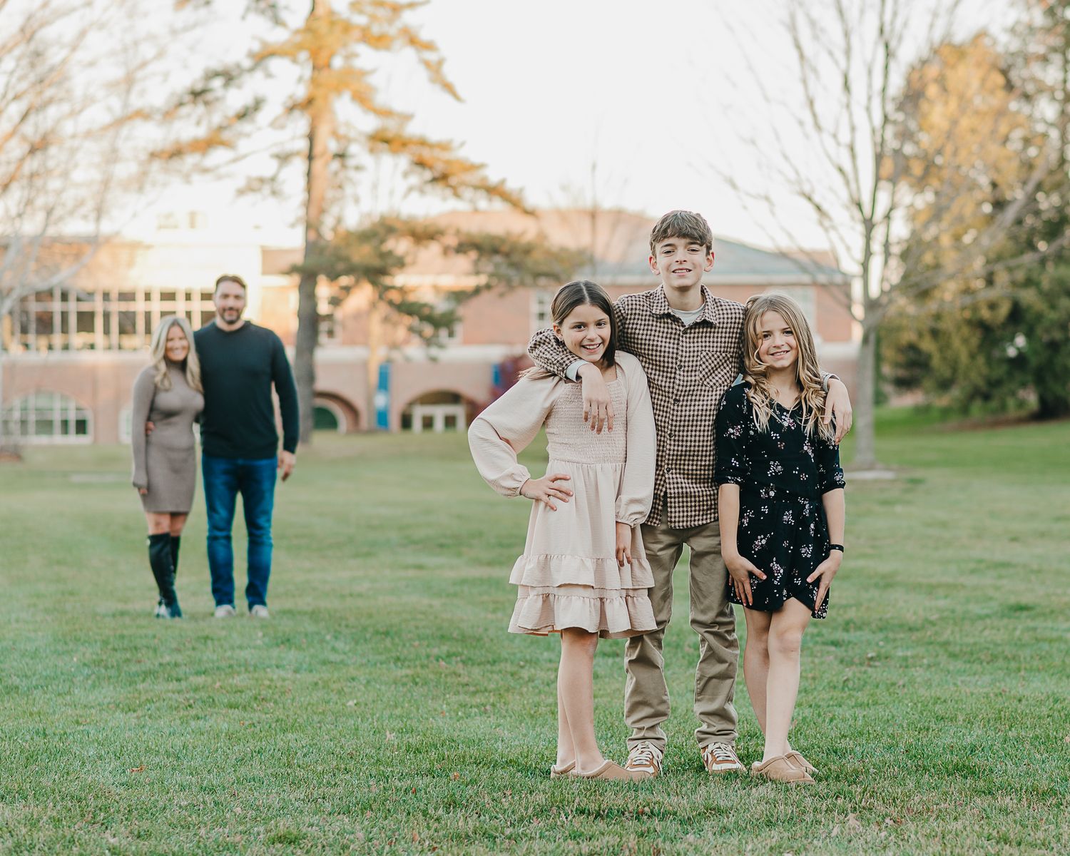Family of five sitting together on outdoor stone steps during a photo session with brick building in background.