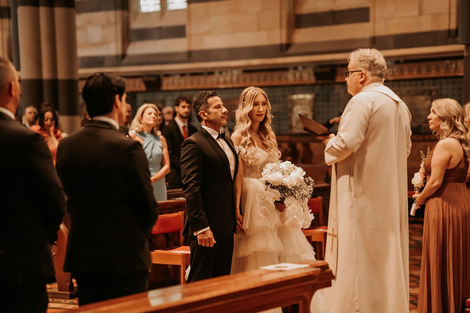 Wedding guests celebrate and dance during the reception in a rustic wooden church venue.