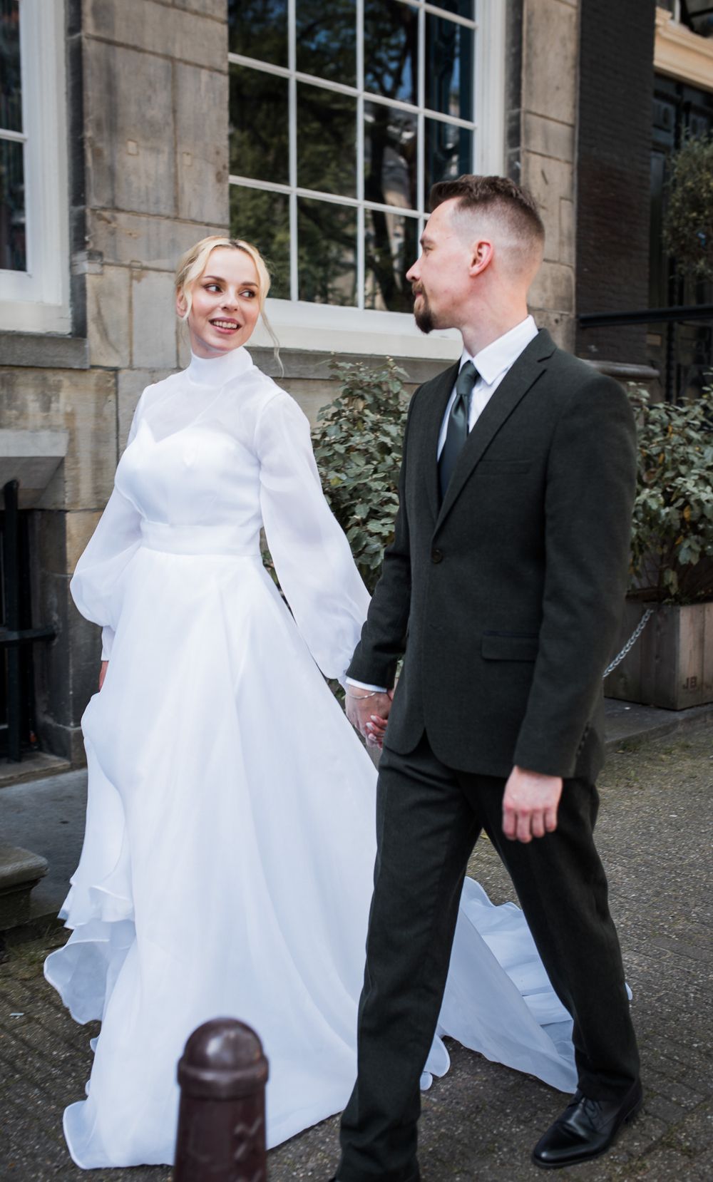 Bride and groom walking the streets of Amsterdam holding hands– elegant city wedding.