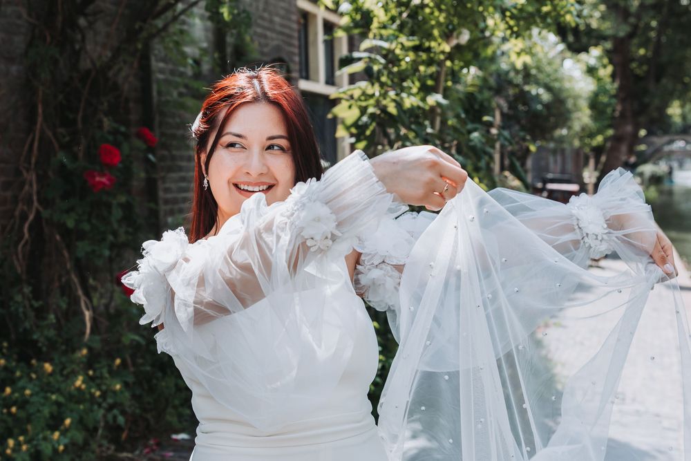 A bride in a twirls her veil playfully along the canal in Utrecht
