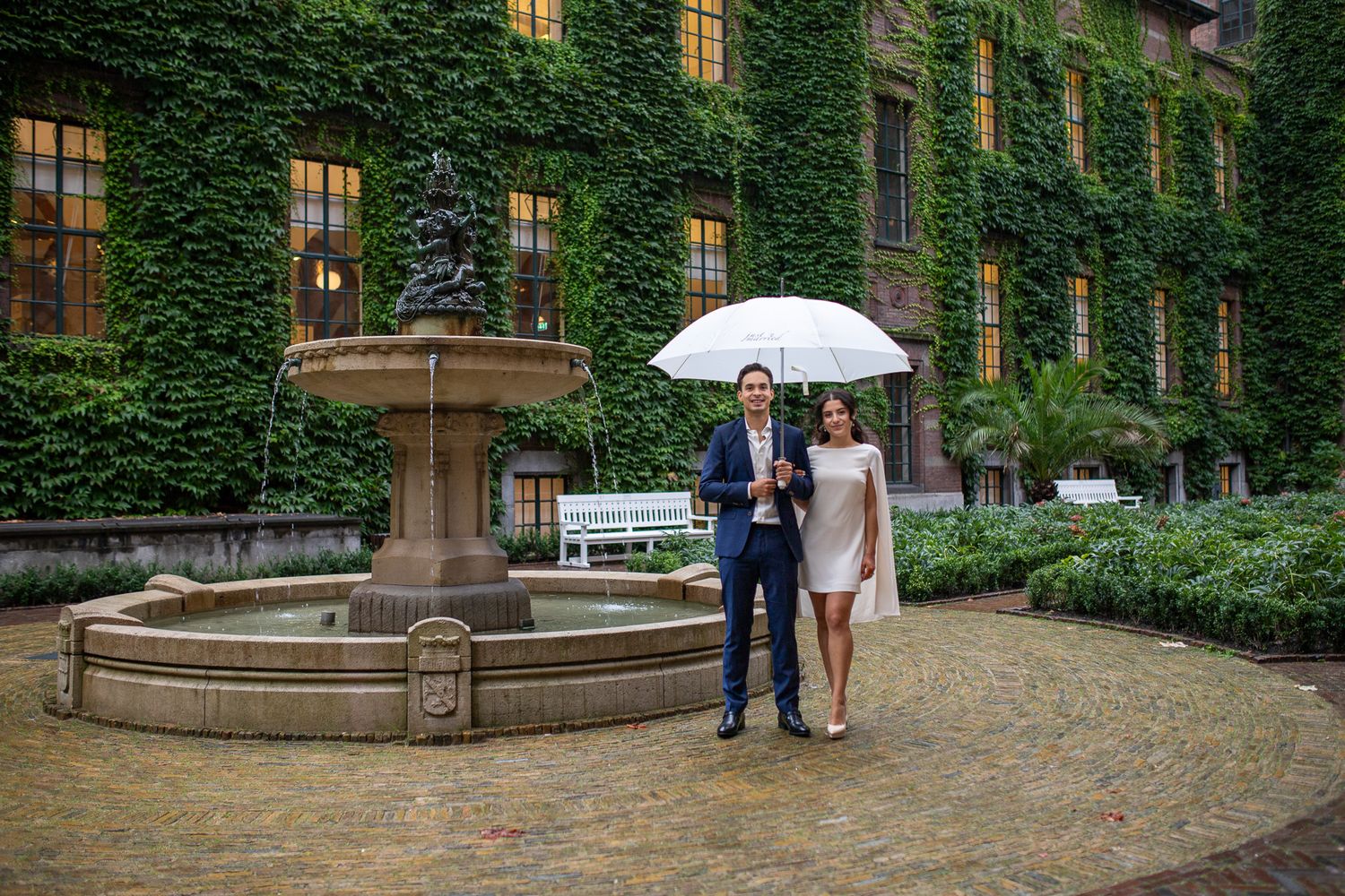 Bridal couple stands in front of an ivy-covered stone building after wedding in Gemeente Rotterdam.